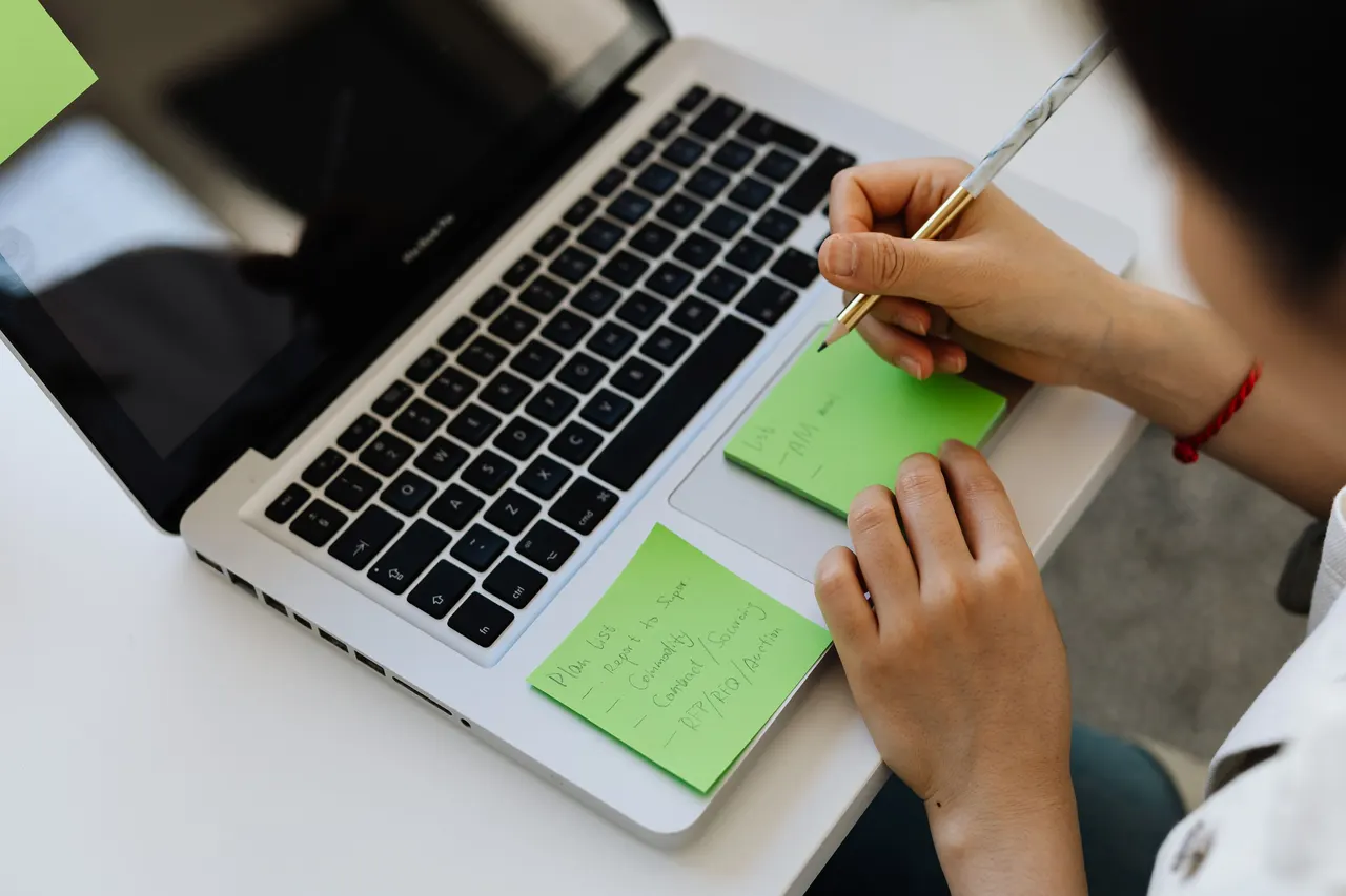 Person Writing on Green Sticky Notes